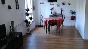 A spacious living area with a dining table, chairs, a TV, and a bookshelf. - Bohemian chic apartment in the heart of the Antigone district (Montpellier)