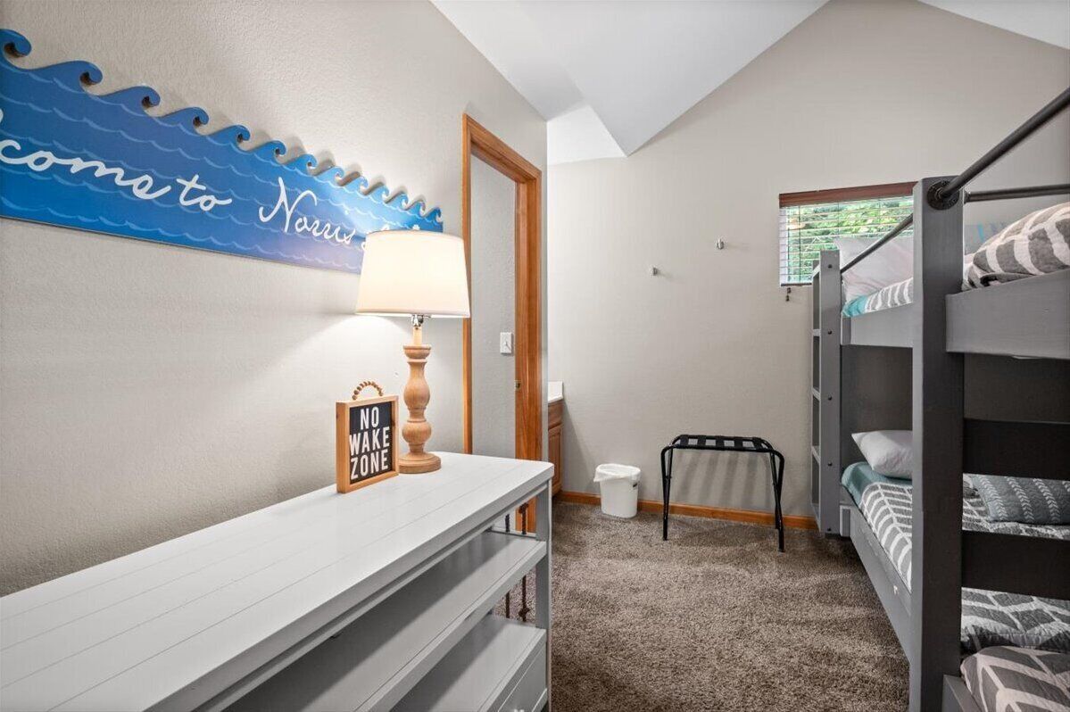 A bedroom with bunk beds, a bedside table with a lamp, a small rug, and a wall decoration.