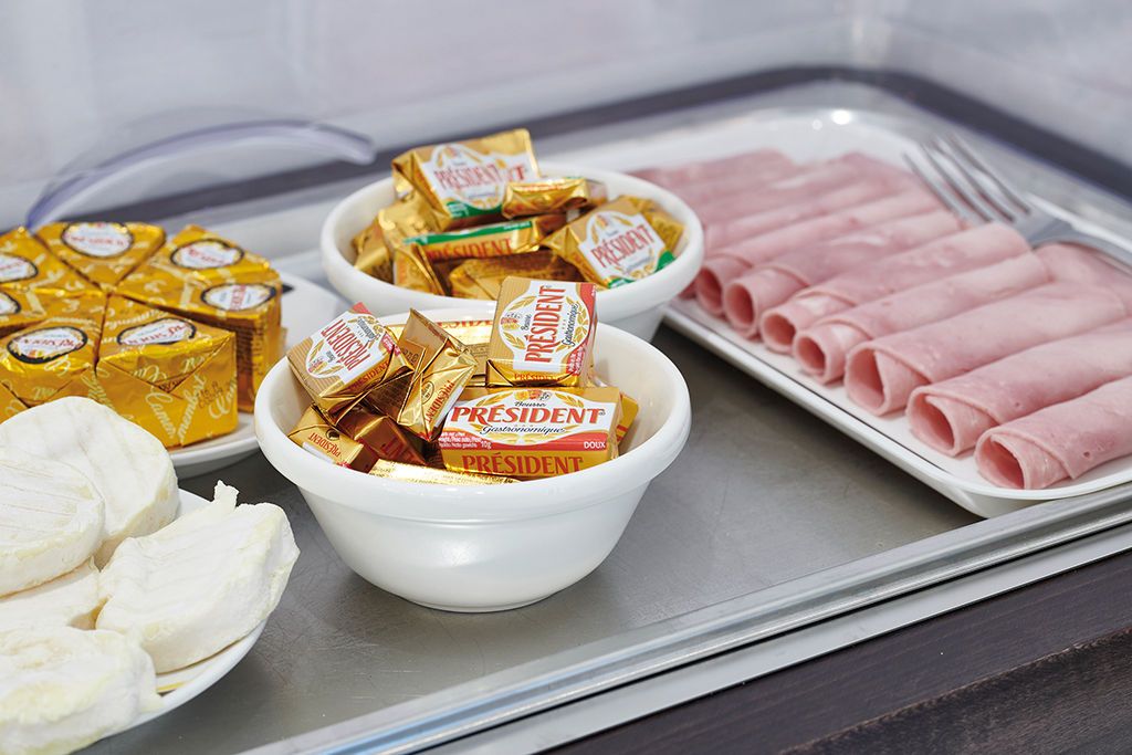 Ett fat med olika sorters mat, inklusive skivad skinka, ost och chokladkakor.
