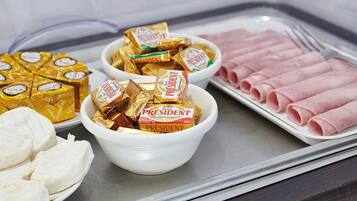 Ett fat med olika sorters mat, inklusive skivad skinka, ost och chokladkakor.