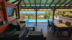 A covered outdoor area with a pool, seating, and a view of the ocean. - Villa Mangotine, luxury villa in deshaies in Guadeloupe (Deshaies)