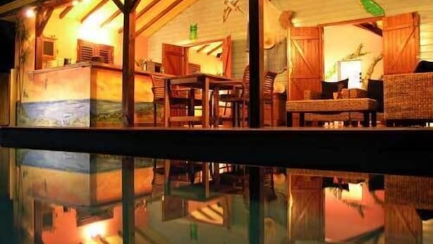 A well-lit indoor area with a pool reflecting the surroundings. - Villa Mangotine, luxury villa in deshaies in Guadeloupe (Deshaies)