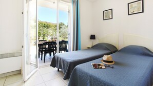 Ein Hotelzimmer mit zwei Betten, einem Essbereich mit Stühlen und Blick ins Freie.