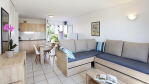 Ein modernes Wohnzimmer mit einer Couch, einem Esstisch und einer Küche im Hintergrund.