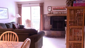 Ein Wohnzimmer mit einer Couch, einem Kamin, einem Esstisch und einem Bücherregal.
