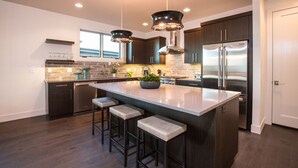 Una cocina moderna con armarios de madera oscura, electrodomésticos de acero inoxidable y una isla central con taburetes de bar.
