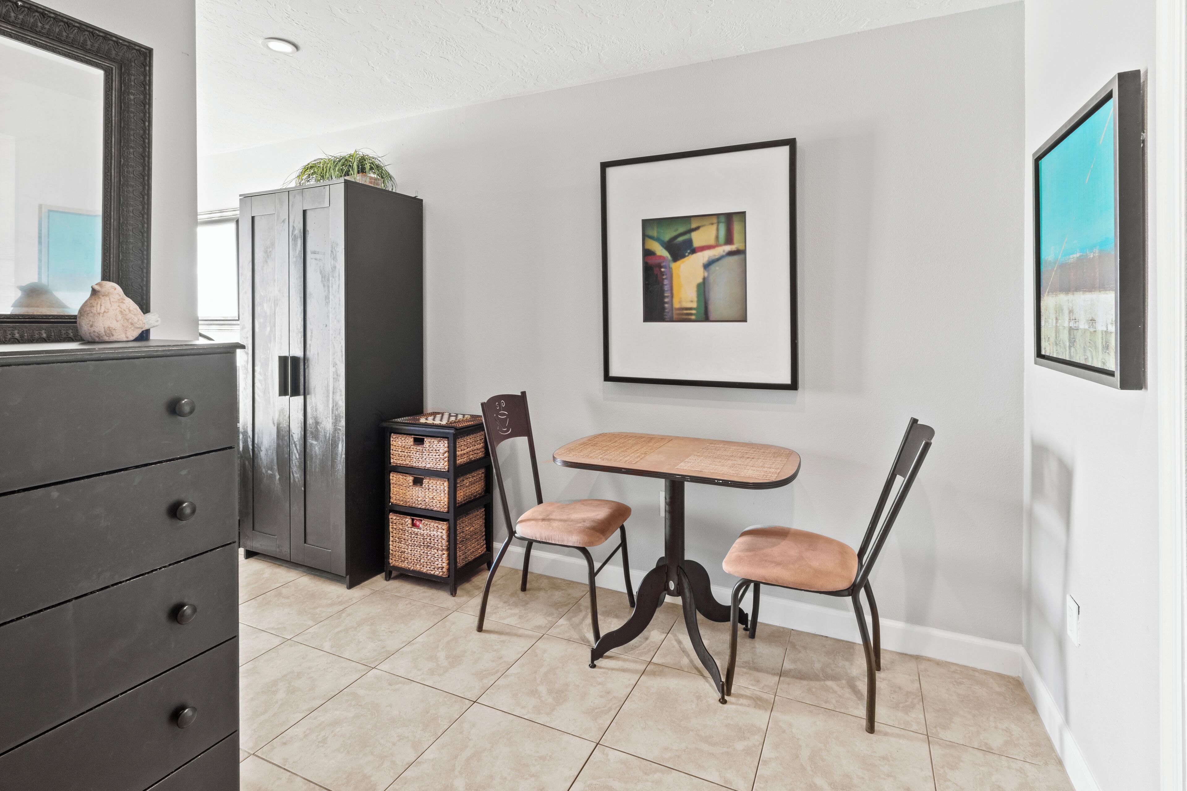Een eethoek met een tafel, stoelen, een kast en een lijst met een afbeelding aan de muur.