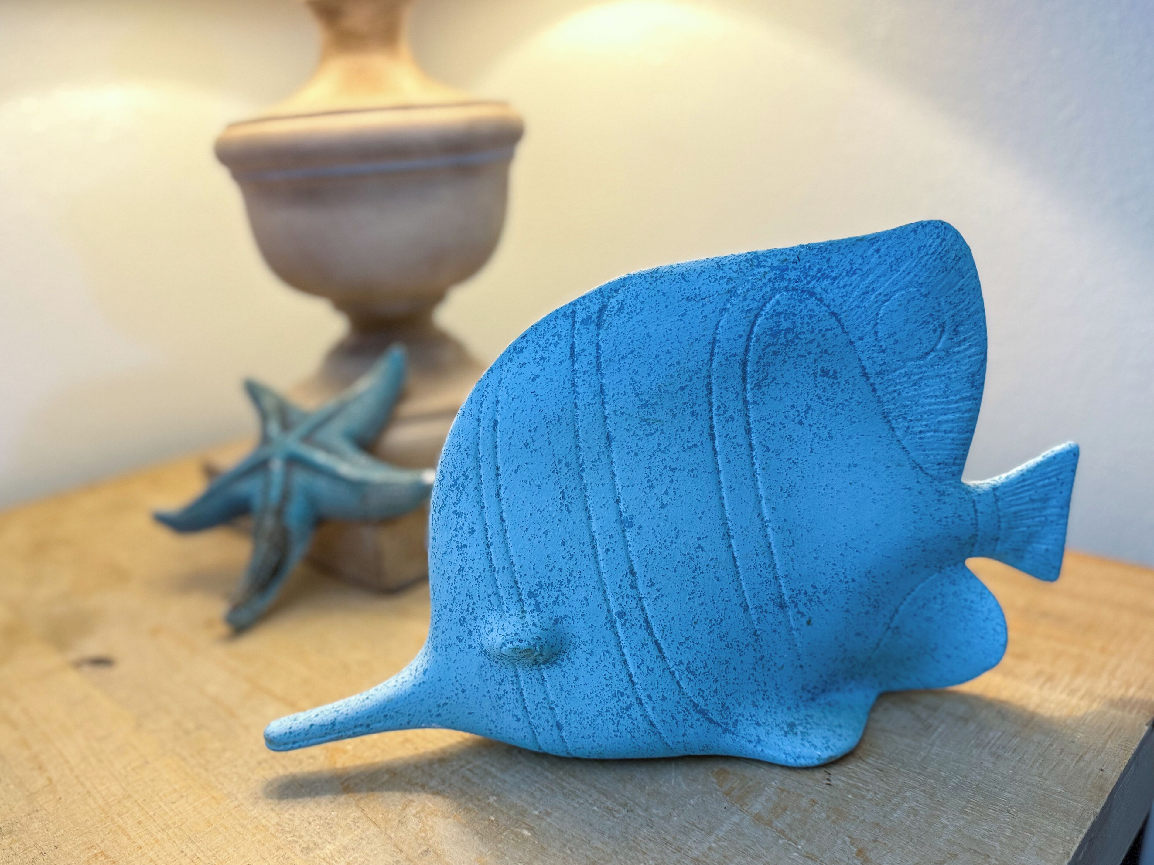 A blue fish-shaped object on a wooden surface.