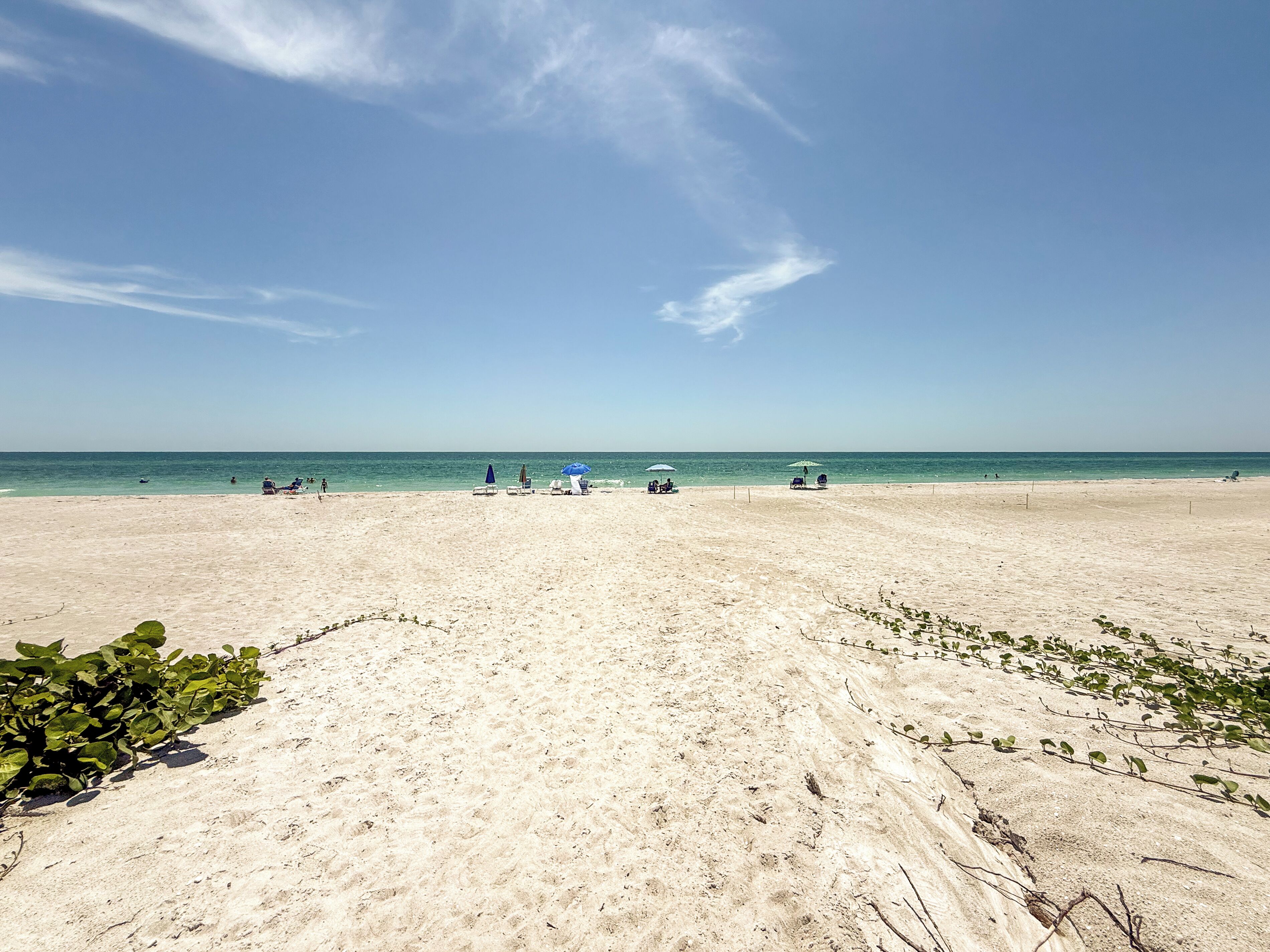 A wide sandy beach with a clear blue sky and calm sea.
