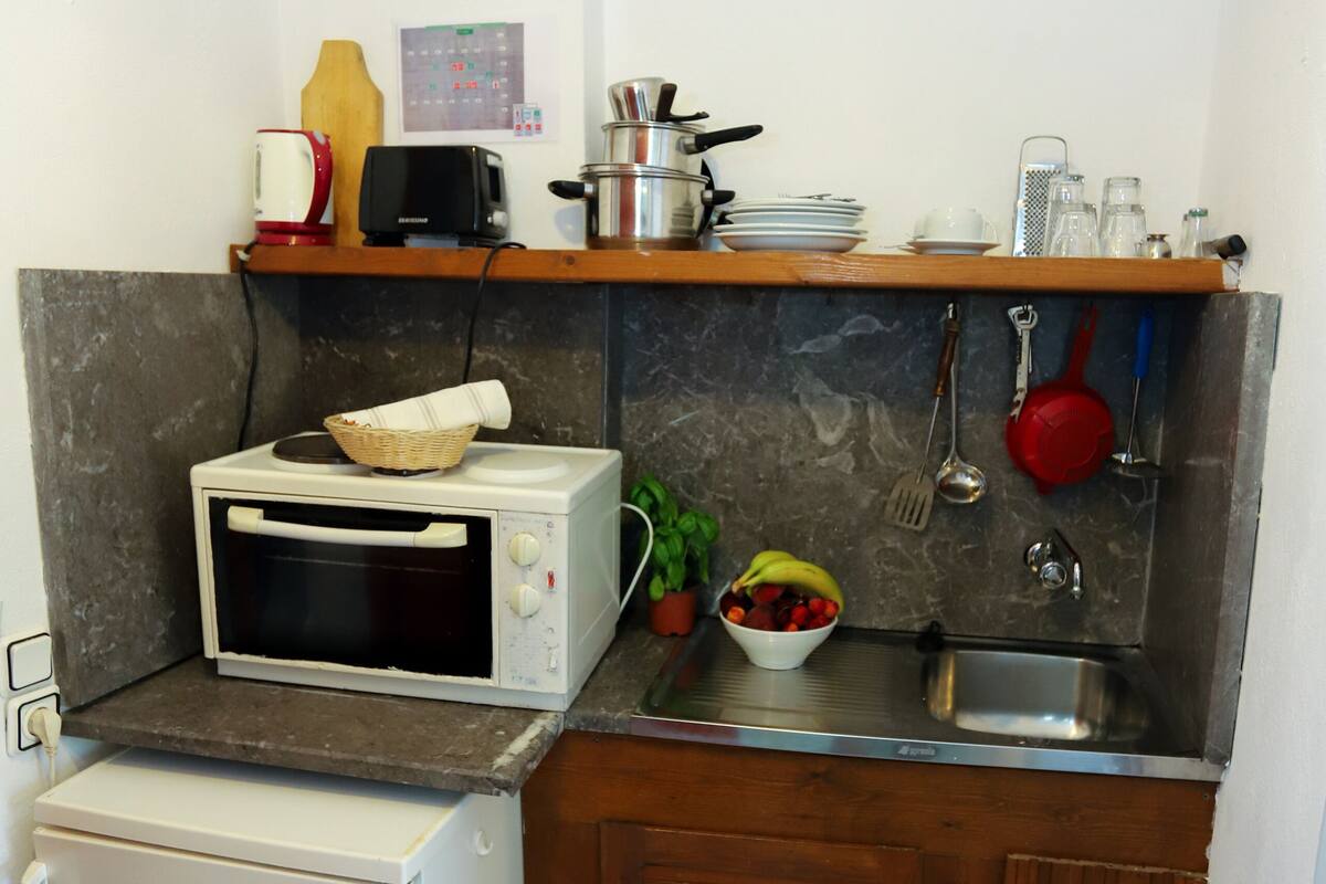 A compact kitchen with a microwave, toaster, sink, and a small refrigerator.