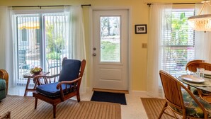 Un salon avec un canapé, une table à manger dressée pour deux personnes et une porte donnant sur un balcon.