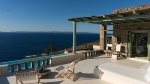 Une terrasse avec vue sur la mer, un bâtiment en pierre et une piscine.