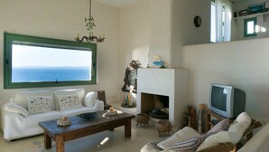 Un salon avec un canapé blanc, une table basse en bois, une cheminée et un téléviseur.
