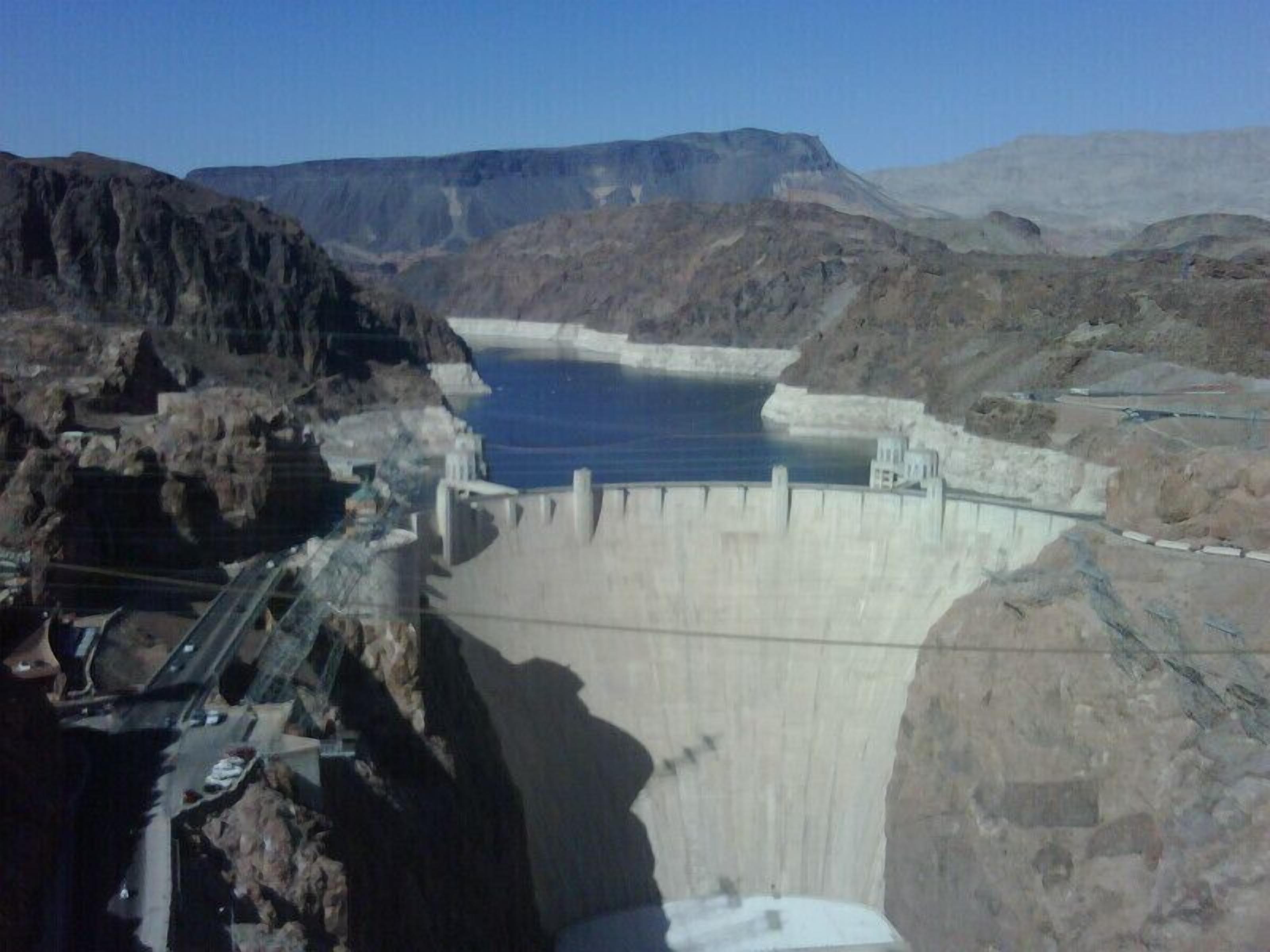 Un barrage avec un réservoir, un terrain rocheux et un ciel dégagé.