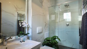 A modern bathroom with a marble sink, a glass shower enclosure, and a potted plant. - Split Centre VIVERE Apartment (Split)