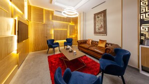 A modern living room with a red rug, leather sofa, and blue chairs. - Hercules Boutique Hotel (Ceuta)