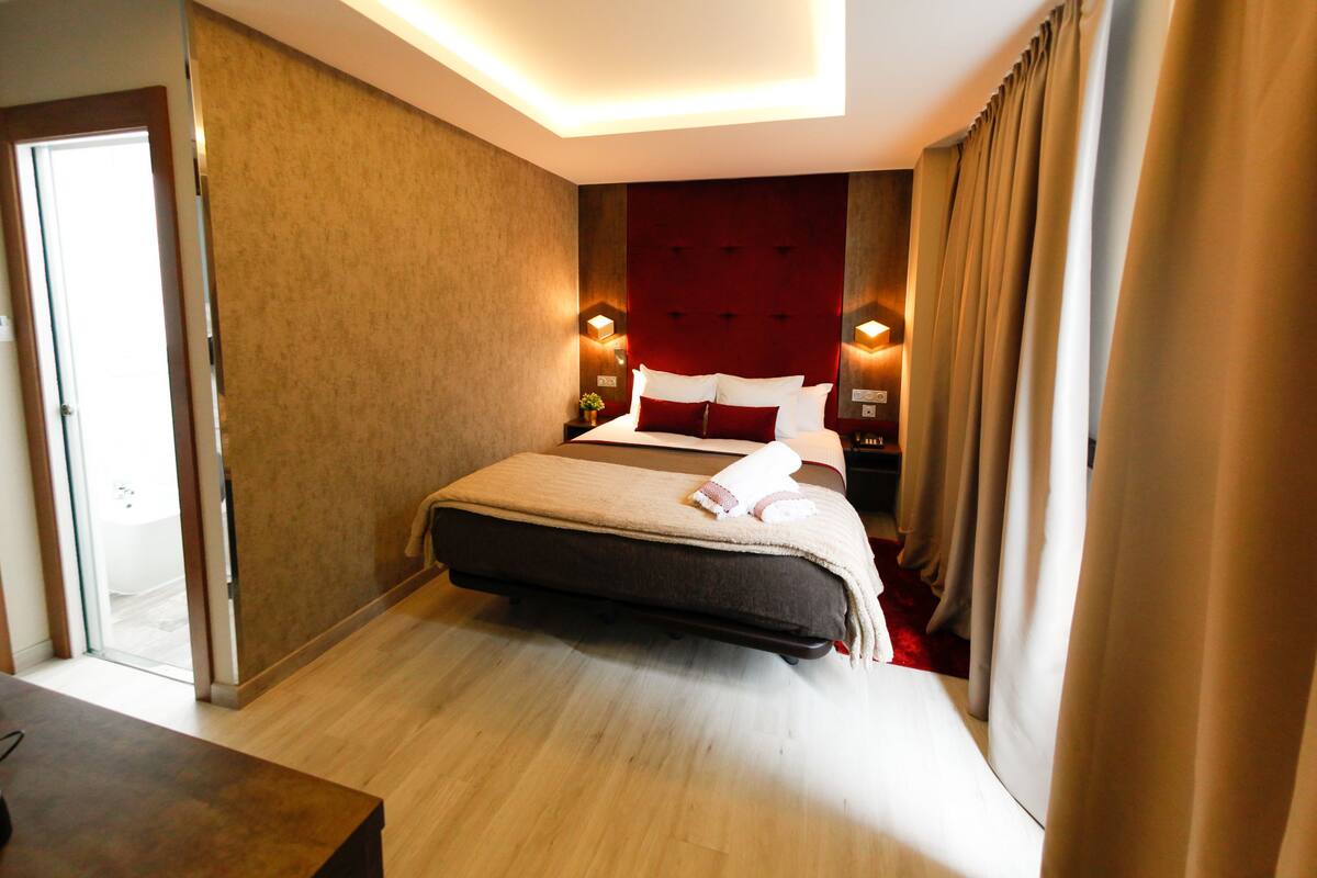 Una habitación de hotel con una cama, mesitas de noche y una puerta.