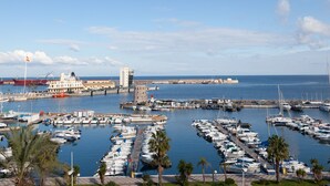 A marina with numerous boats docked, a prominent building with a tower, and a clear view of the sea. - Hercules Boutique Hotel (Ceuta)