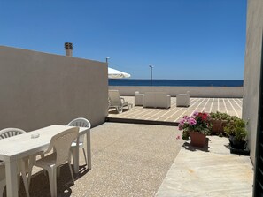 A terrace with a table and chairs, a potted plant, and a view of the sea. - The Casa delle Zie in Gallipoli, in the center with a beautiful sea view (Gallipoli)
