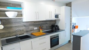 A modern kitchen with white cabinets, a black countertop, a microwave, and a dishwasher. - Modern house overlooking the sea, near the beach in Almadraba, Roses (ROSES)