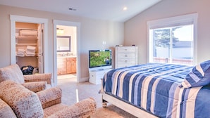 A bedroom with a bed, a TV, a dresser, a closet, and a window.