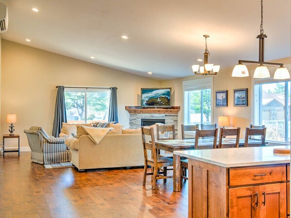 A spacious living room with a fireplace, a dining area with wooden chairs, and a kitchen island.