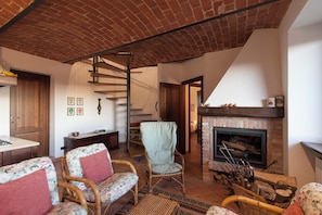 Una sala de estar rústica con techo de ladrillo, chimenea y mobiliario de mimbre.