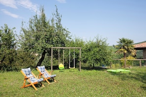 Un jardín con un columpio, dos sillas de jardín y una piscina pequeña.