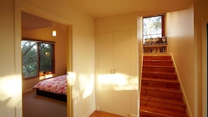 Un dormitorio con cama, armario y una escalera con vistas al exterior.