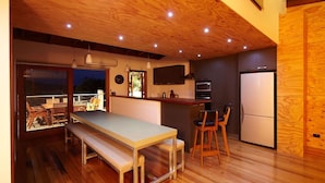 Una cocina moderna con suelo de madera, una mesa de comedor con bancos, un refrigerador y un microondas.