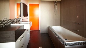 Un baño moderno con una bañera grande, ducha y tocador con espejo.