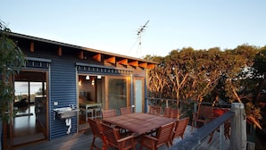 Una casa moderna con terraza, zona de comedor y cocina visibles a través de puertas de cristal.