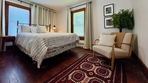 Ein Schlafzimmer mit Bett, Stuhl, Fenster und Pflanze.