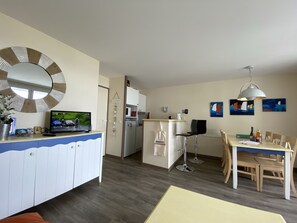 A modern kitchen with a built-in microwave and refrigerator, a dining area with a table and chairs, and a large mirror on the wall.