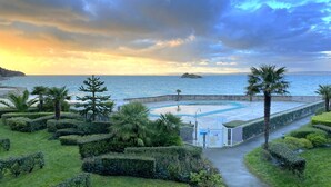 A pool area with a view of the sea, surrounded by well-maintained hedges and palm trees. - dZI8, a place like no other ... for a successful holiday! (Douarnenez)