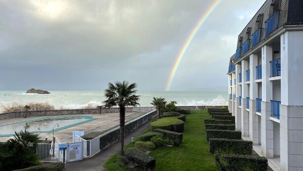 A view of a hotel with a pool, a garden, and a view of the sea with waves crashing against a rocky outcrop. - dZI8, a place like no other ... for a successful holiday! (Douarnenez)