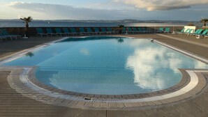 A swimming pool with a view of the sea, surrounded by lounge chairs and a stone wall. - dZI8, a place like no other ... for a successful holiday! (Douarnenez)