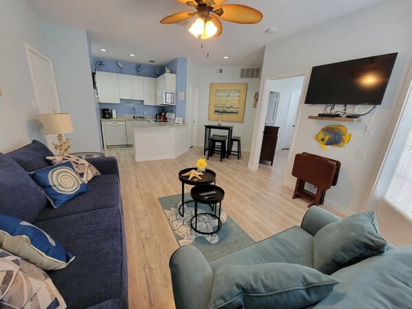 A modern living room with a sofa, a coffee table, and a TV mounted on the wall.