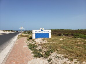 A sign for Whitecap Beach with a clear road and beach in the background.