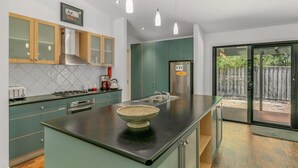 Una cocina moderna con gabinetes verdes, encimera negra y una isla grande con un bol.