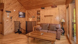 A wooden interior with a sofa, a coffee table, a lamp, and a bookshelf. - Rocking Bear: Mtn View! Pets, S/Secluded, Hot Tub, Wifi, Games, Spacious Decks! (Sevierville)