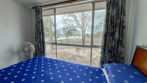 A room with a bed, a standing fan, and a window with curtains. - Stafford Hall - Burrum Heads- Riverfront- 3BR- Great Views (BURRUM HEADS)