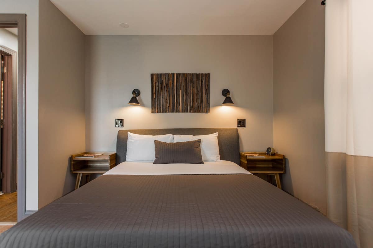 A neatly made bed with a headboard, two bedside tables with lamps, and a wall-mounted artwork above the bed.