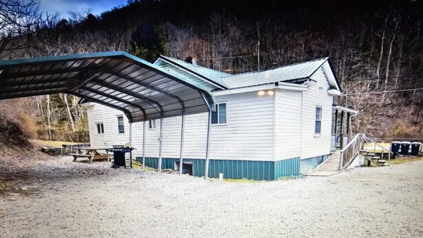 A two-story building with a covered outdoor area, a staircase leading to the upper floor, and a small porch. - Spacious riding retreat 4 BR Outlaw House/ ATV Riding 10beds-Large Parking (Northfork)