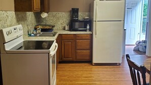 A kitchen with wooden cabinets, a white refrigerator, a microwave, and a stove. - Spacious riding retreat 4 BR Outlaw House/ ATV Riding 10beds-Large Parking (Northfork)