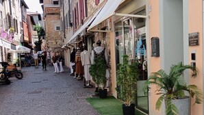 Una calle adoquinada bordeada de edificios, algunos con tiendas y terrazas.