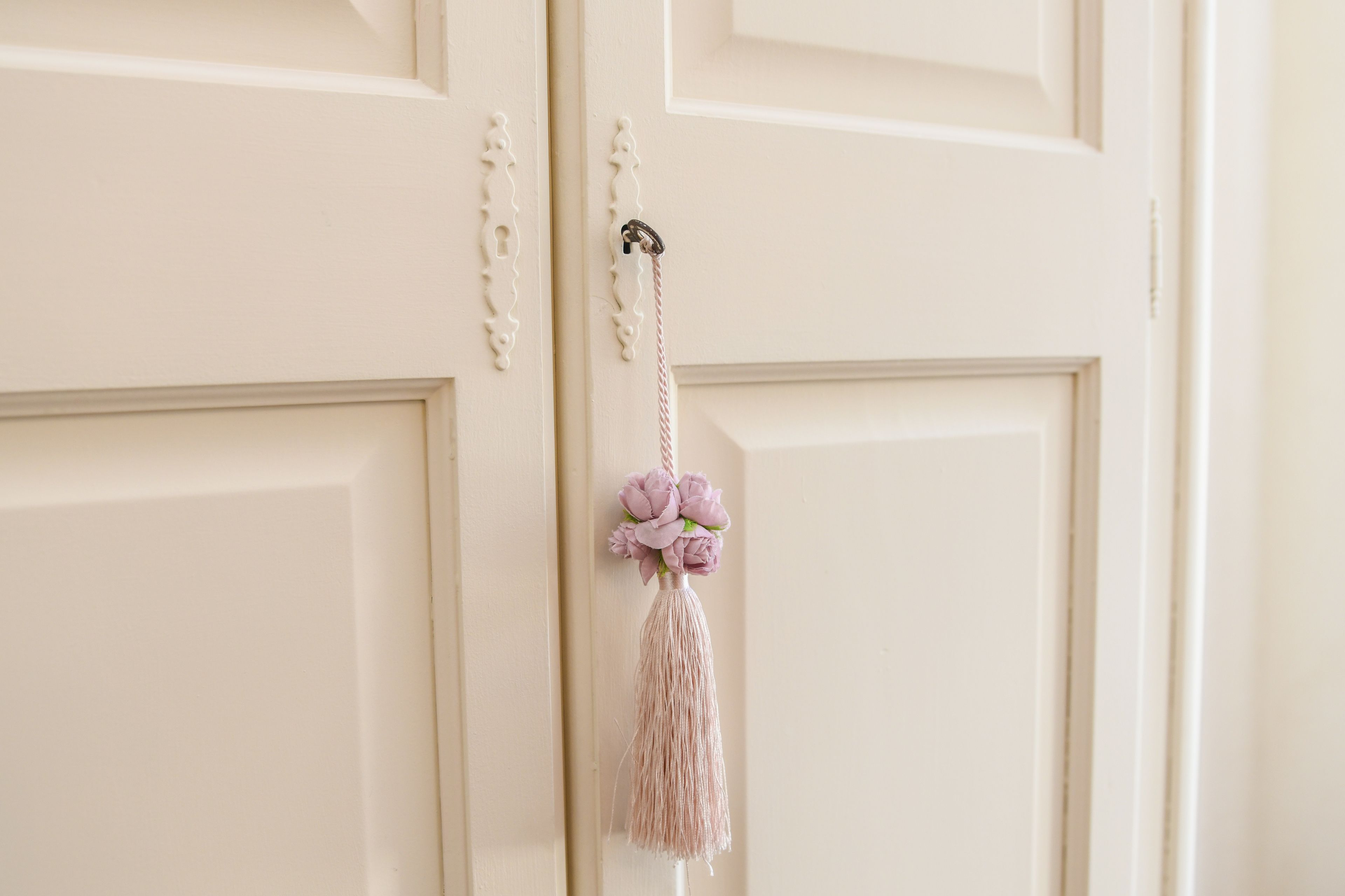 A white door with a decorative tassel and a small floral arrangement.