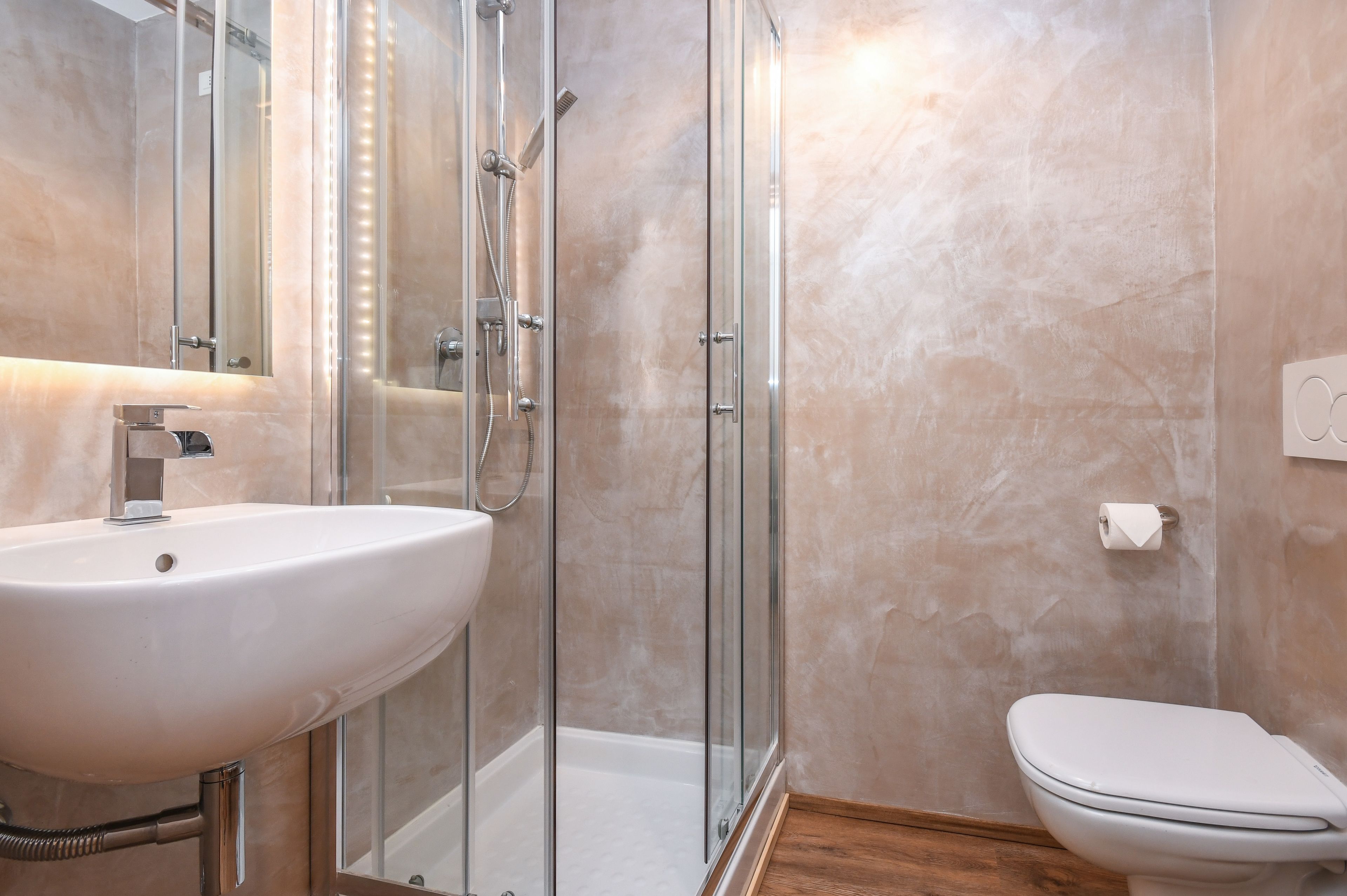 Une salle de bain avec une douche à parois de verre, un lavabo blanc et des toilettes.