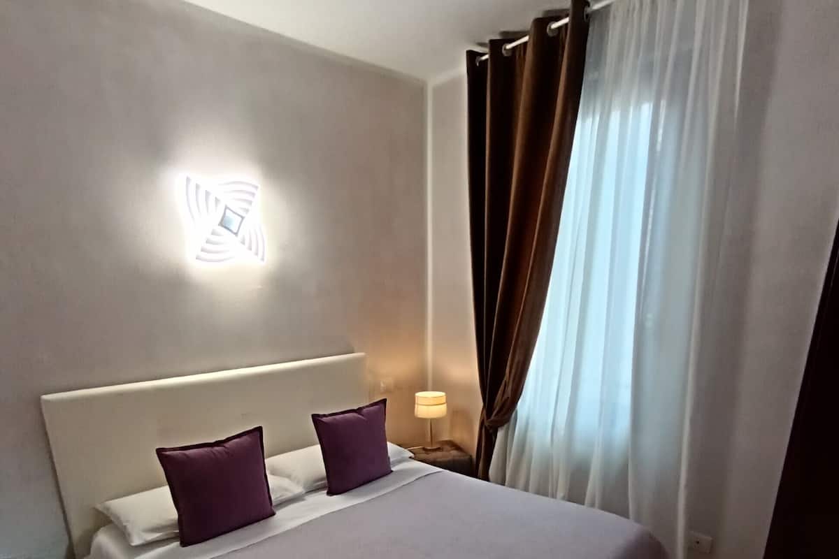 A neatly made bed with a headboard, two pillows, and a bedside lamp.