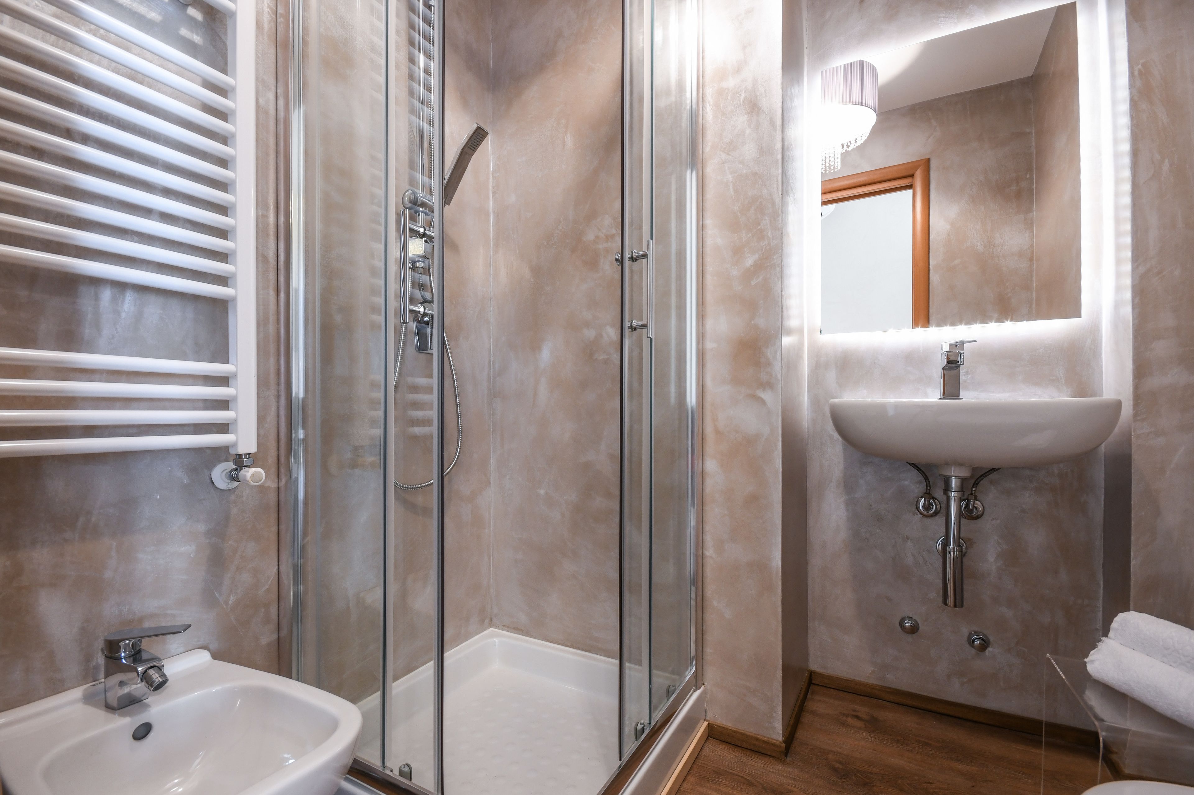 Ein modernes Badezimmer mit einer gläsernen Duschkabine, einem Standwaschbecken und einem Schminkspiegel.